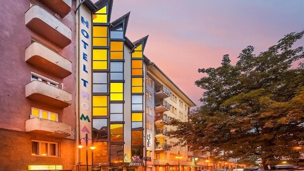 A hotel with a modern facade, multiple balconies, and a prominent sign. - Thomas Hotel Budapest (Budapest)