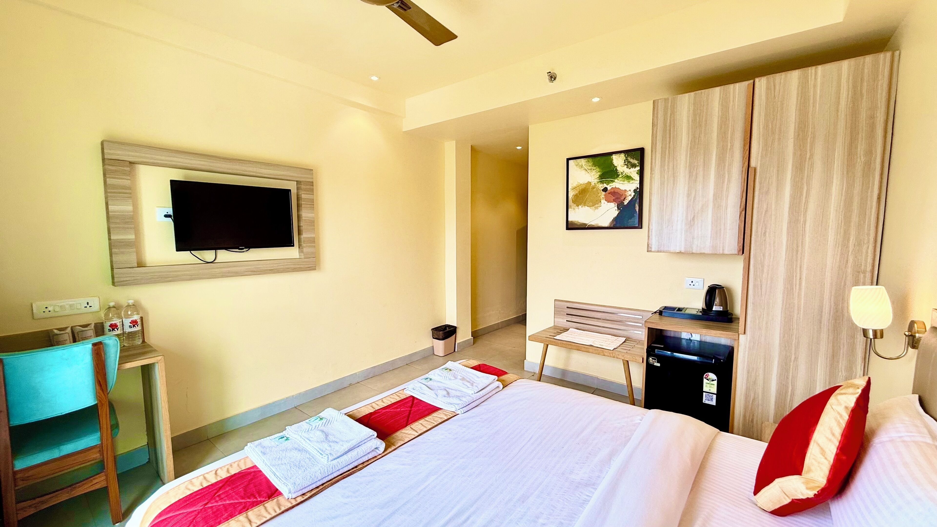 A hotel room with a bed, a desk, a chair, a TV, and a wardrobe.