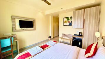 A hotel room with a bed, a desk, a chair, a TV, and a wardrobe.