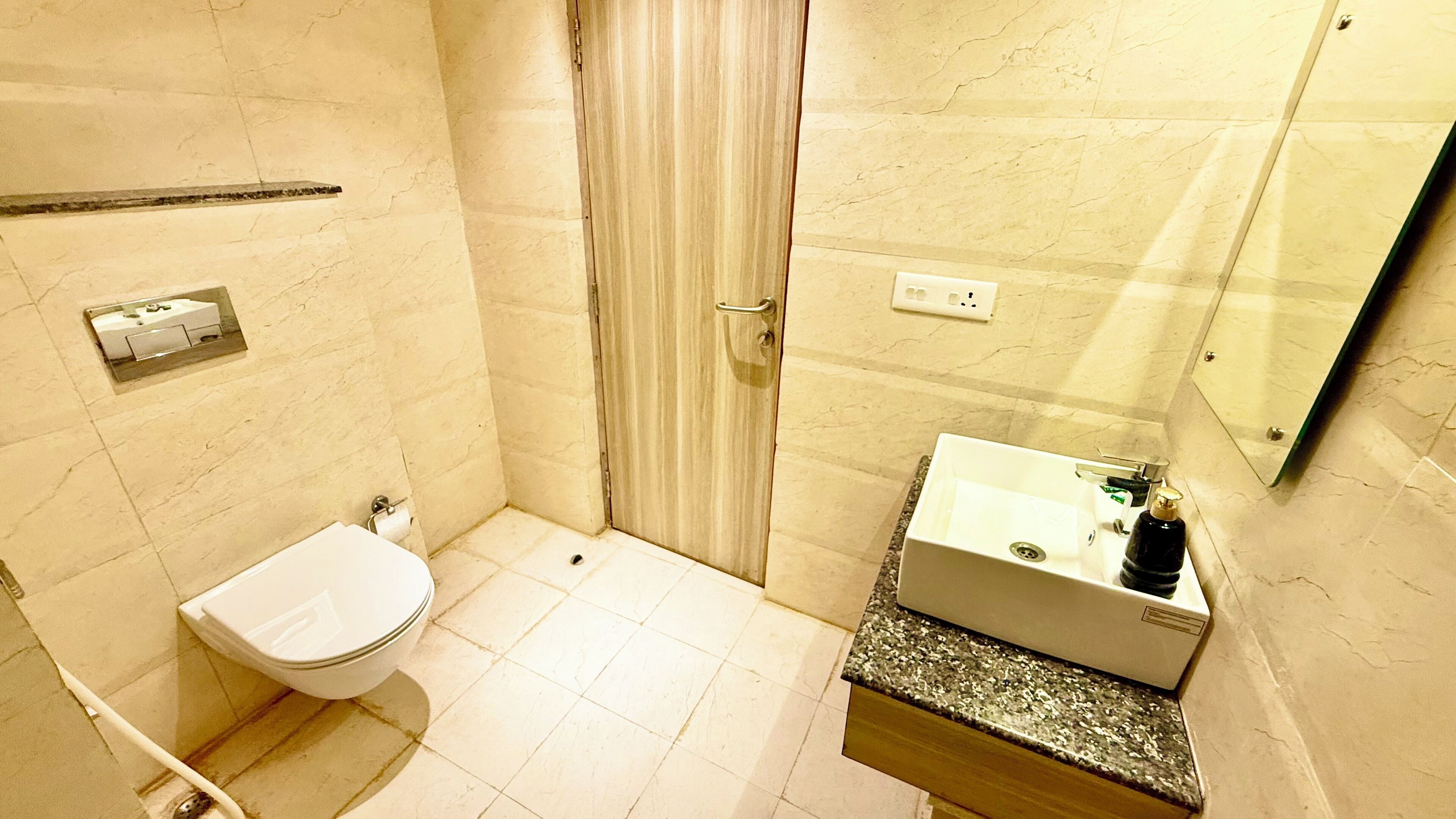 A bathroom with a toilet, sink, mirror, and shower area.