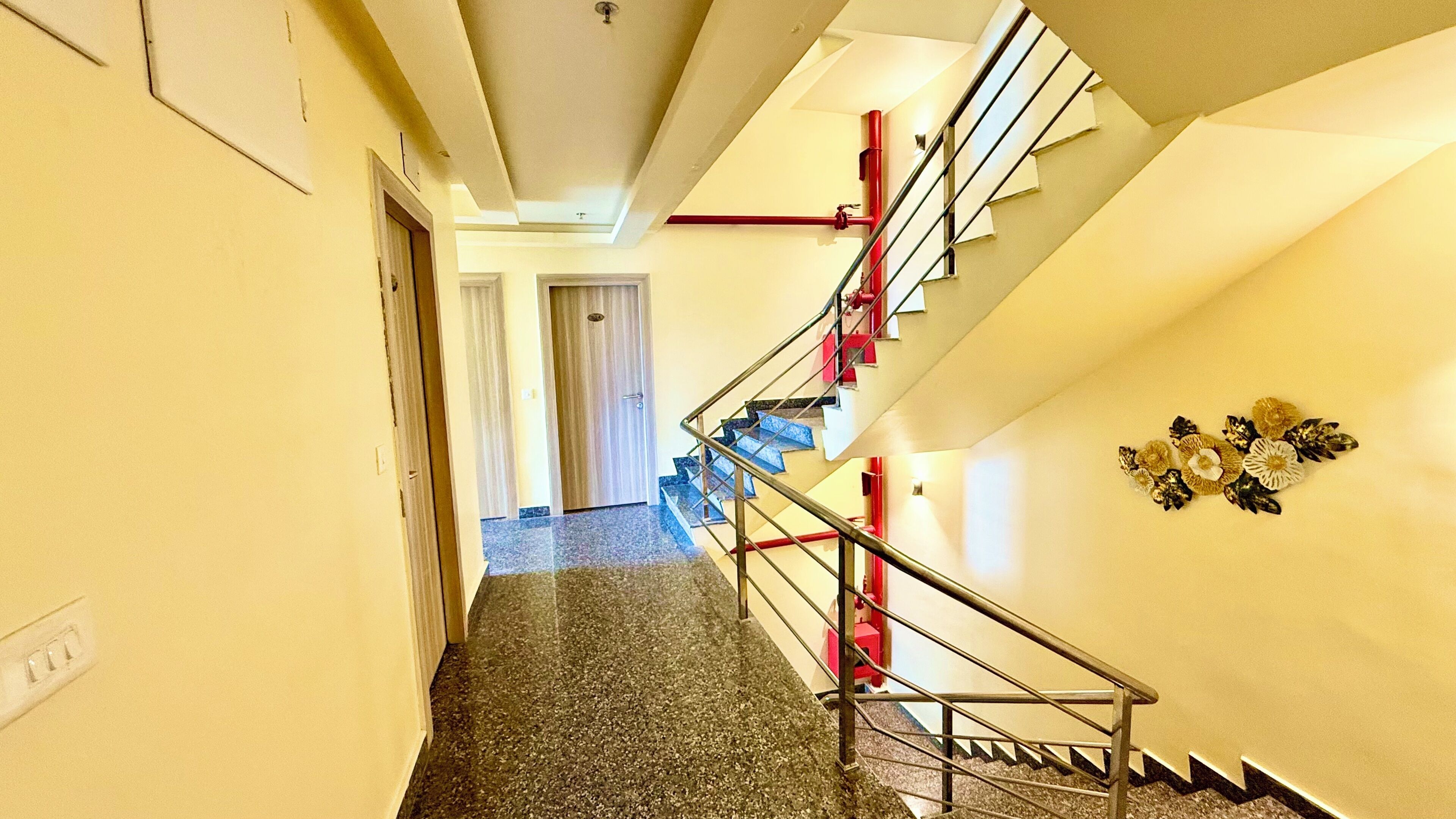 A hallway with a staircase, carpeted floor, and a door at the end.