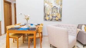 Un comedor con una mesa de madera dispuesta para cuatro personas, un sofá y un cuadro en la pared.