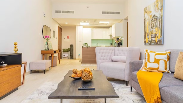 Una sala moderna con sofá, mesa de centro y un comedor con cocina al fondo.