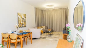 Una sala moderna con comedor, un conjunto de sofá, una mesa de centro y un espejo grande.