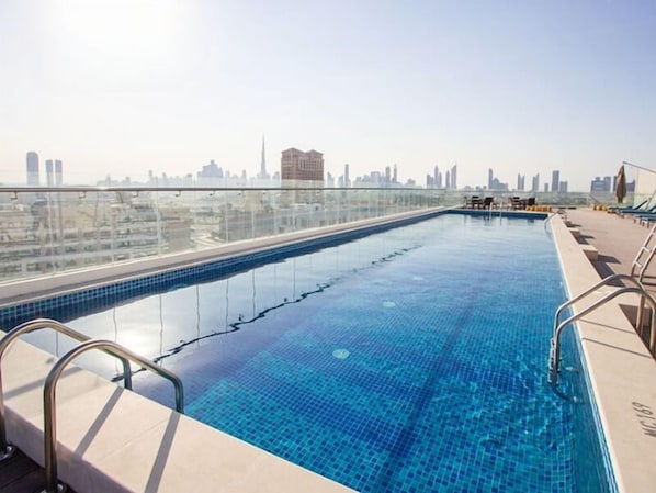 A rooftop infinity pool with a city skyline view. - Bloomfields 1BR - Aliya Azizi - Al Jaddaf (Dubai)