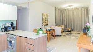 Una sala de estar moderna con sofá, mesa de comedor y zona de cocina con lavadora.