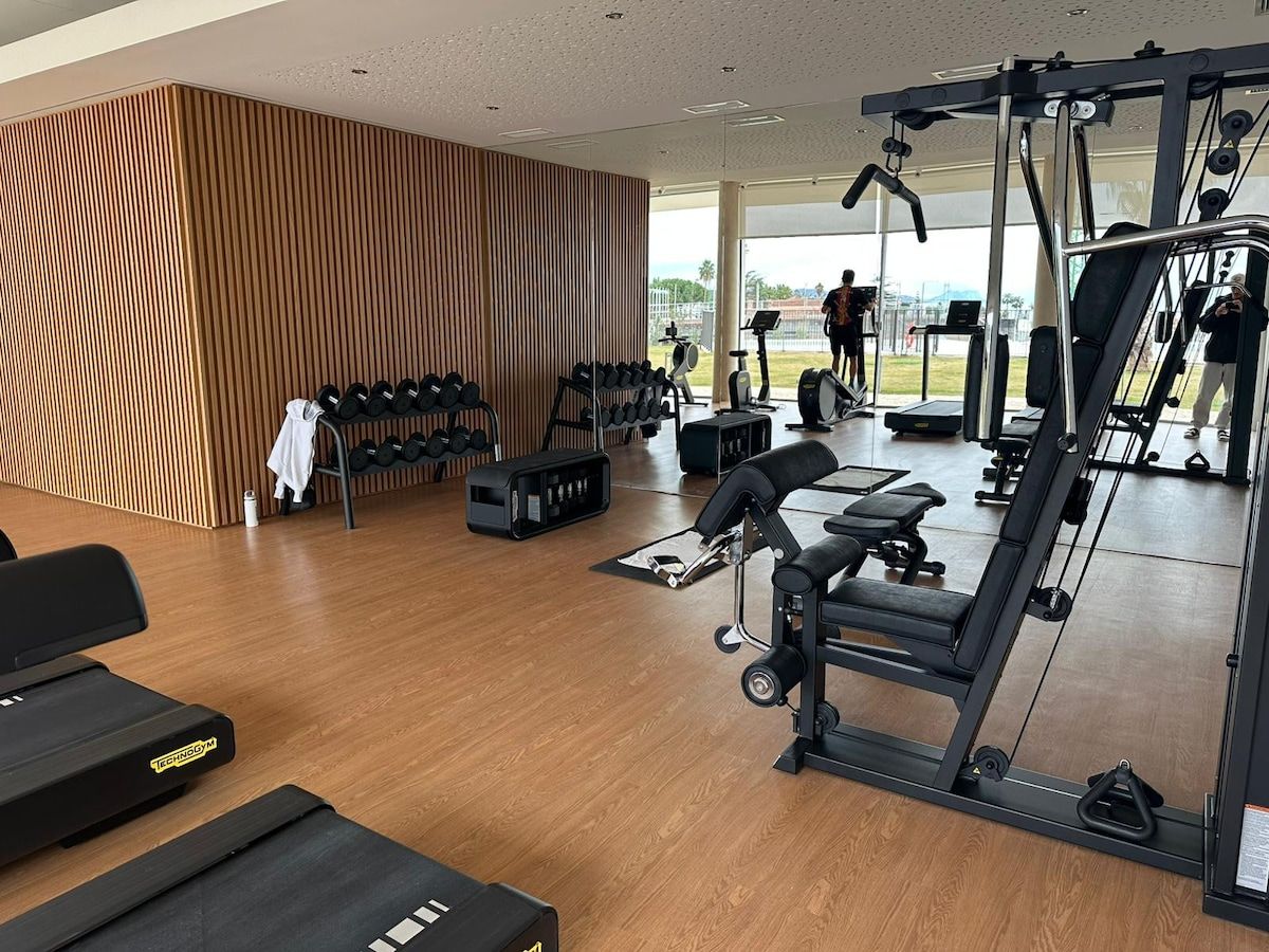 A gym with exercise equipment, a wooden wall, and a view of the outdoors.