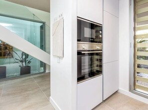 A modern kitchen with a built-in oven and a glass door refrigerator. - Casa Sol Estepona | Private Pool - Garden - Views (Estepona)
