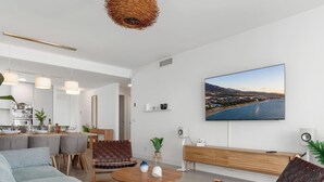 Ett modernt vardagsrum med en matplats, ett stort fönster med utsikt över staden och en platt-TV som är monterad på väggen.