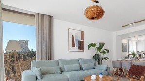 Ett modernt vardagsrum med en ljusblå soffa, ett soffbord i trä och en hängande lampa av rotting.