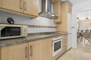 Eine Küche mit Holzausstattung, einer Mikrowelle, einem Backofen und einem Ventilator.