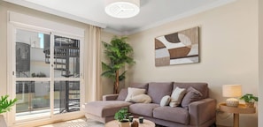 Ein modernes Wohnzimmer mit einem grauen Sofa, einem Couchtisch und einem Blumentopf.