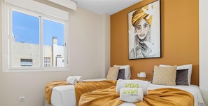 Ein Hotelzimmer mit zwei Betten, einem großen Fenster und einem Gemälde an der Wand.