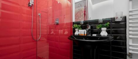 Une salle de bain moderne avec des murs recouverts de carreaux rouges, un lavabo noir et une douche en verre.