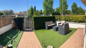 A patio with outdoor furniture, a small garden area, and a wooden fence. - Relaxation in Holiday House Calmasino (Veneto)
