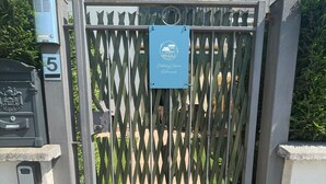 A gated entrance with a metal gate, a sign indicating 'Holiday Home Coliassino', and a number '5' sign on the wall. - Relaxation in Holiday House Calmasino (Veneto)