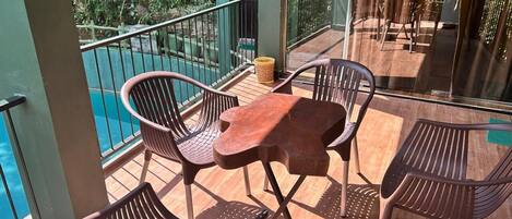 A balcony with wooden flooring, metal railings, and plastic chairs.