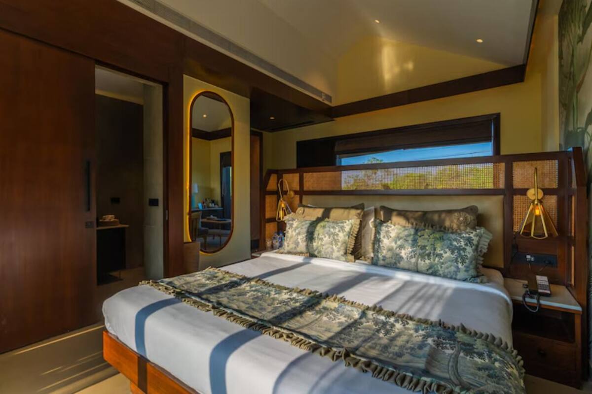 Un dormitorio con una cama grande, cabecera de madera, un espejo y una ventana con vistas.