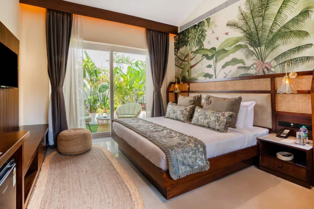 Un dormitorio con una cama grande, televisión, mesita de noche y vistas al exterior.