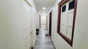 A corridor with white doors, a tiled floor, and a ceiling light. - Shree Gangesh Inn (Varanasi)