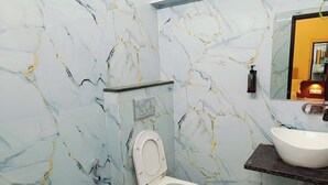 A bathroom with a toilet, a sink, and a mirror. - Shree Gangesh Inn (Varanasi)