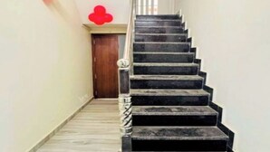 A staircase with black steps and a marble floor leading to a door at the top. - Shree Gangesh Inn (Varanasi)