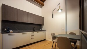 A modern kitchen with a dark countertop, light-colored cabinets, and a wooden dining table with chairs. - Ca Moroni Collection (Bergamo)