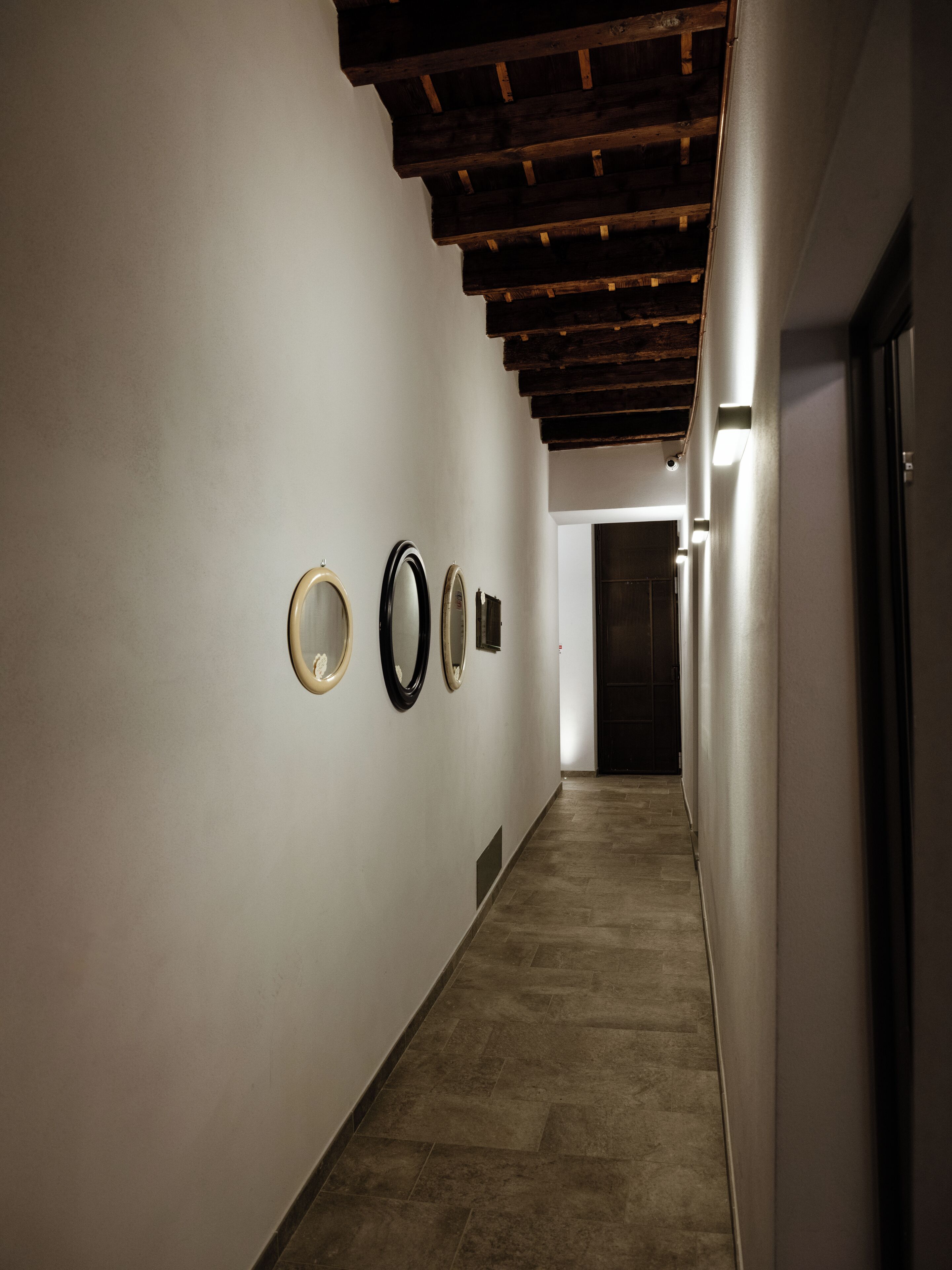 A hallway with a series of framed mirrors on the wall and a door at the end.