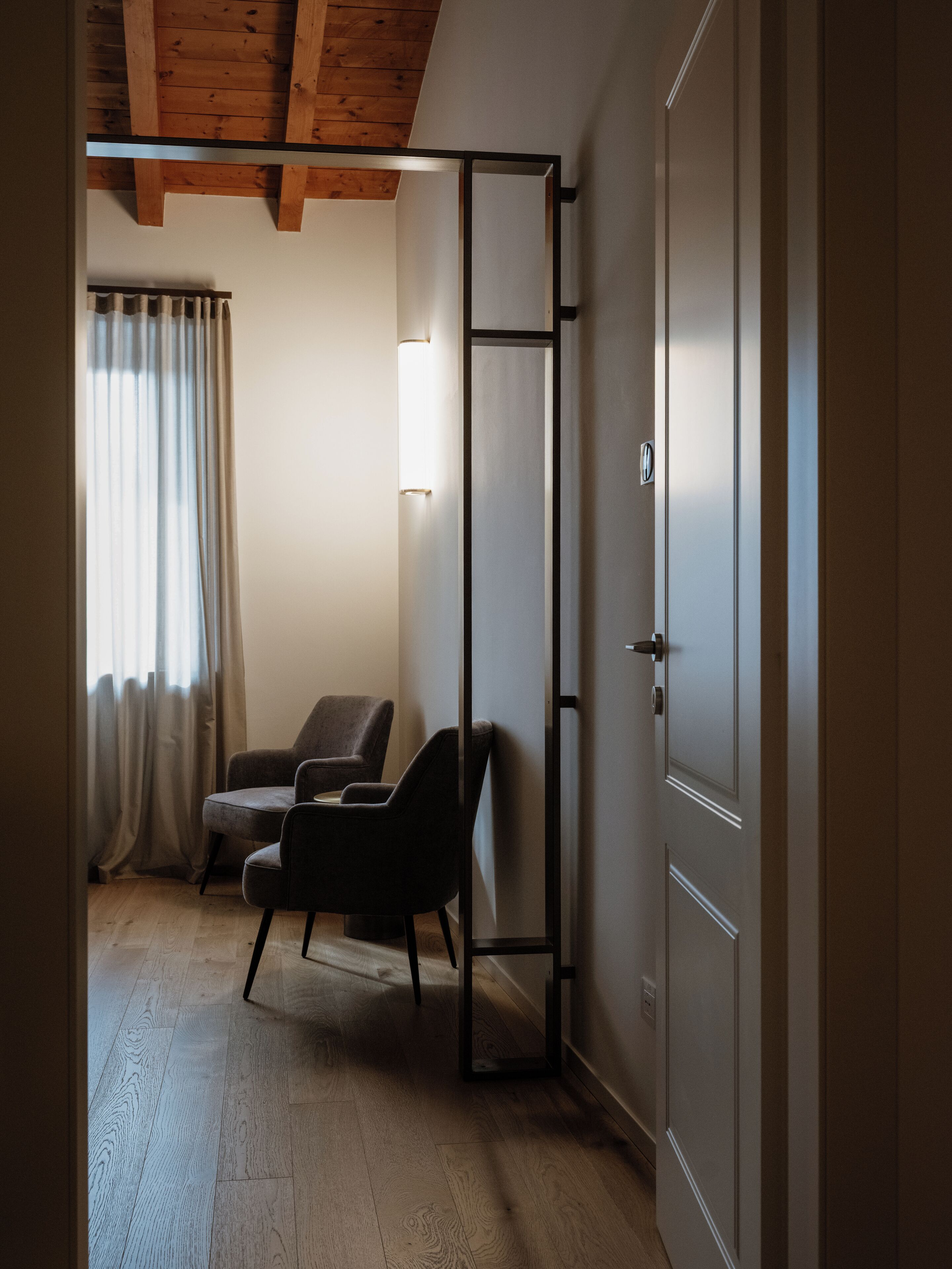 Une pièce avec un plafond en bois, une porte coulissante, une chaise et un rideau.
