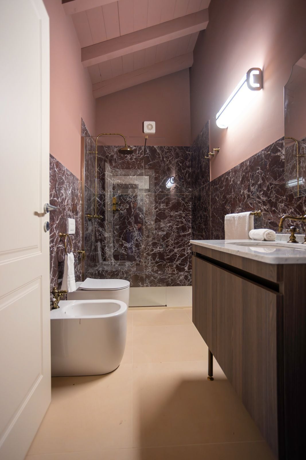 Ein modernes Badezimmer mit einer freistehenden Badewanne, einem Waschtisch inklusive Spiegel und Marmorwänden.