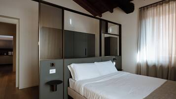 Habitación de hotel con cama, un espejo grande, un armario y una mesita.