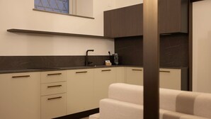 A modern kitchen with a dark countertop, light-colored cabinets, and a window with a geometric pattern. - Ca Moroni Collection (Bergamo)