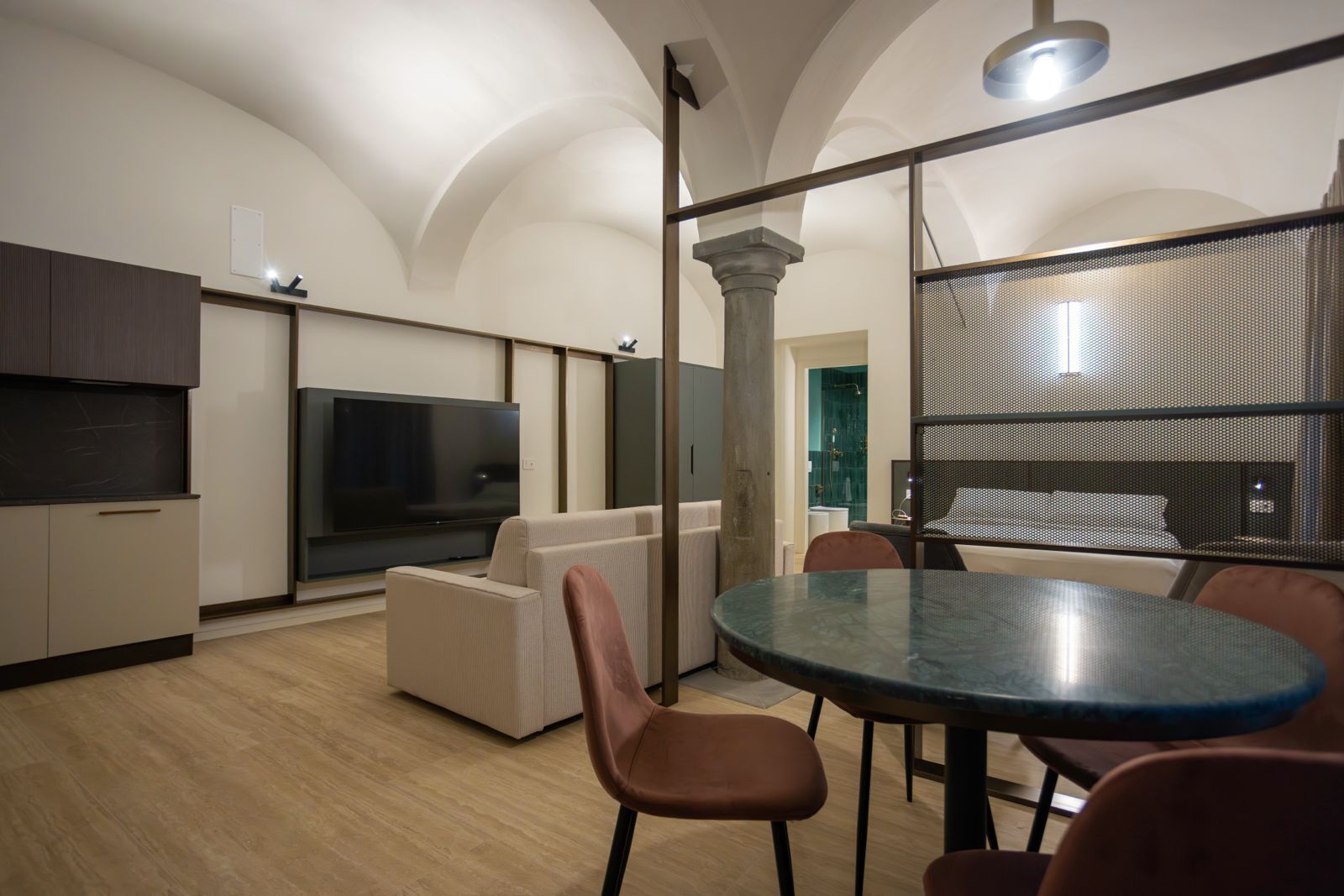 Uma sala de estar moderna com televisão de tela plana, um sofá, uma mesa de jantar com cadeiras e uma janela grande.