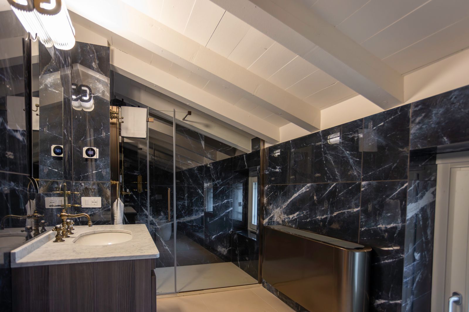 A modern bathroom with a marble sink, a large mirror, and a glass-enclosed shower.