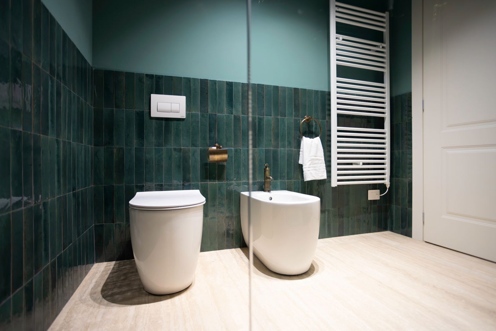 A modern bathroom with a toilet, sink, and towel rack.