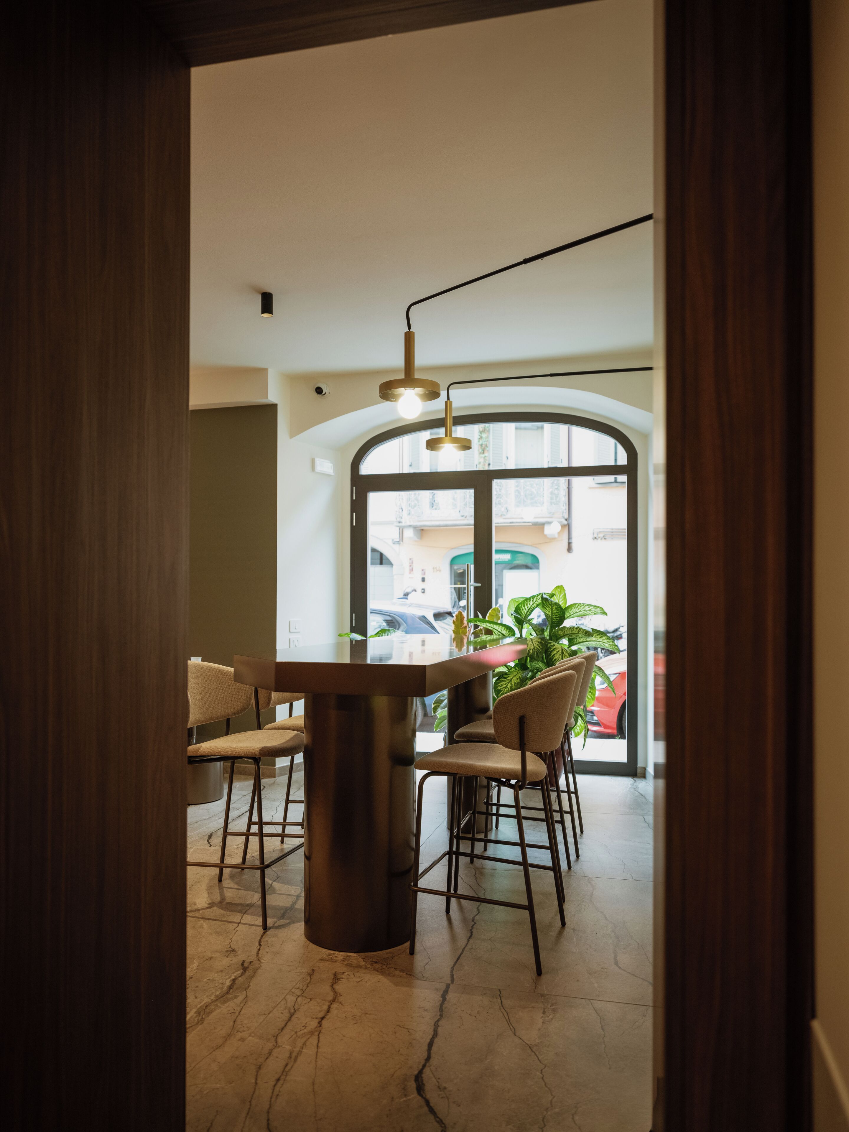 A modern dining area with a marble floor, a central round table, and four chairs.
