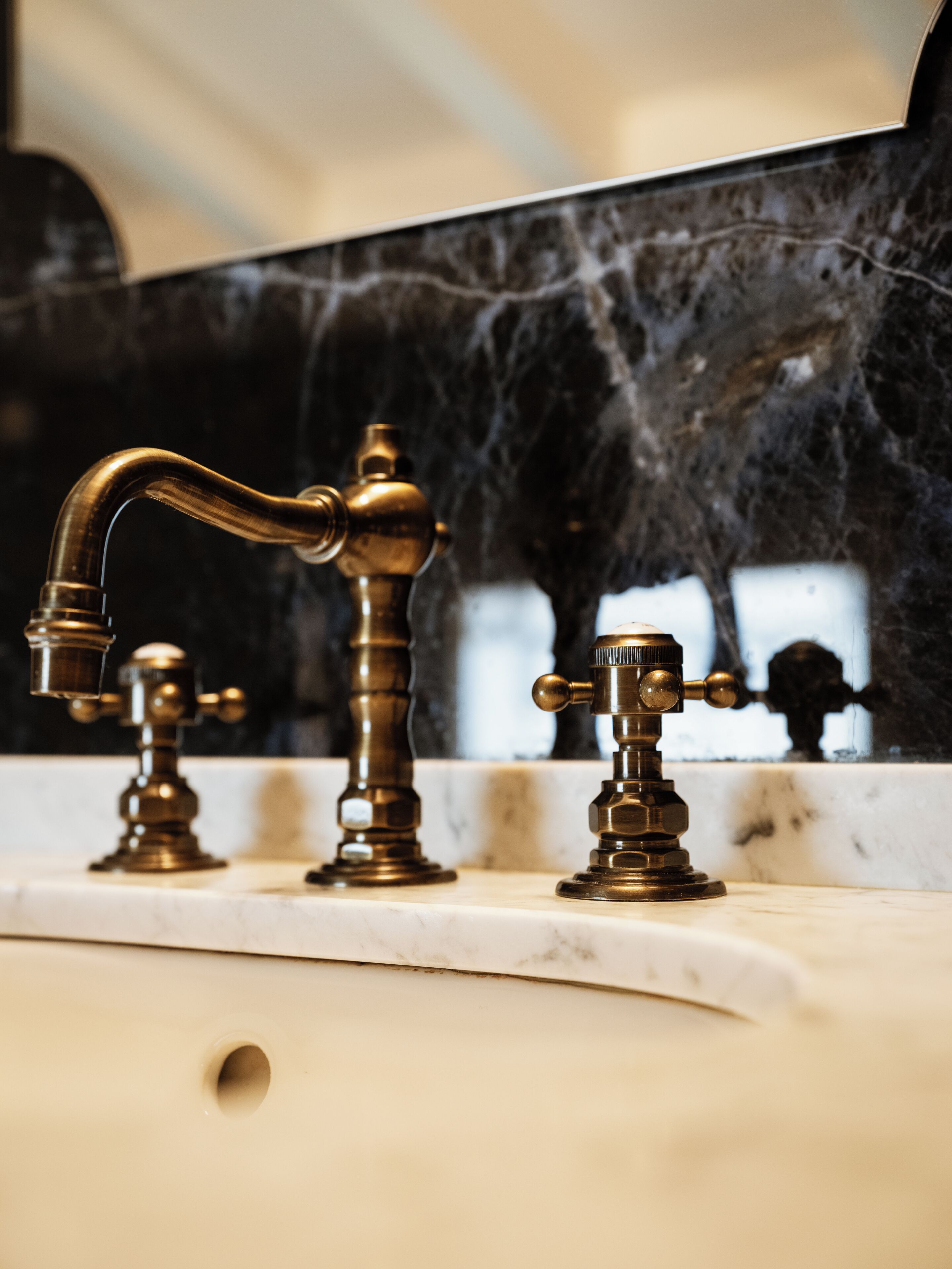 A bathroom with a marble sink and brass fixtures.
