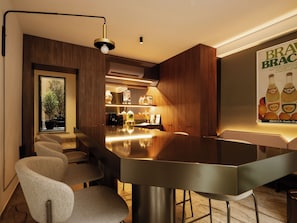 A modern kitchen with a bar area, wooden cabinetry, and a poster advertising Bracca.
