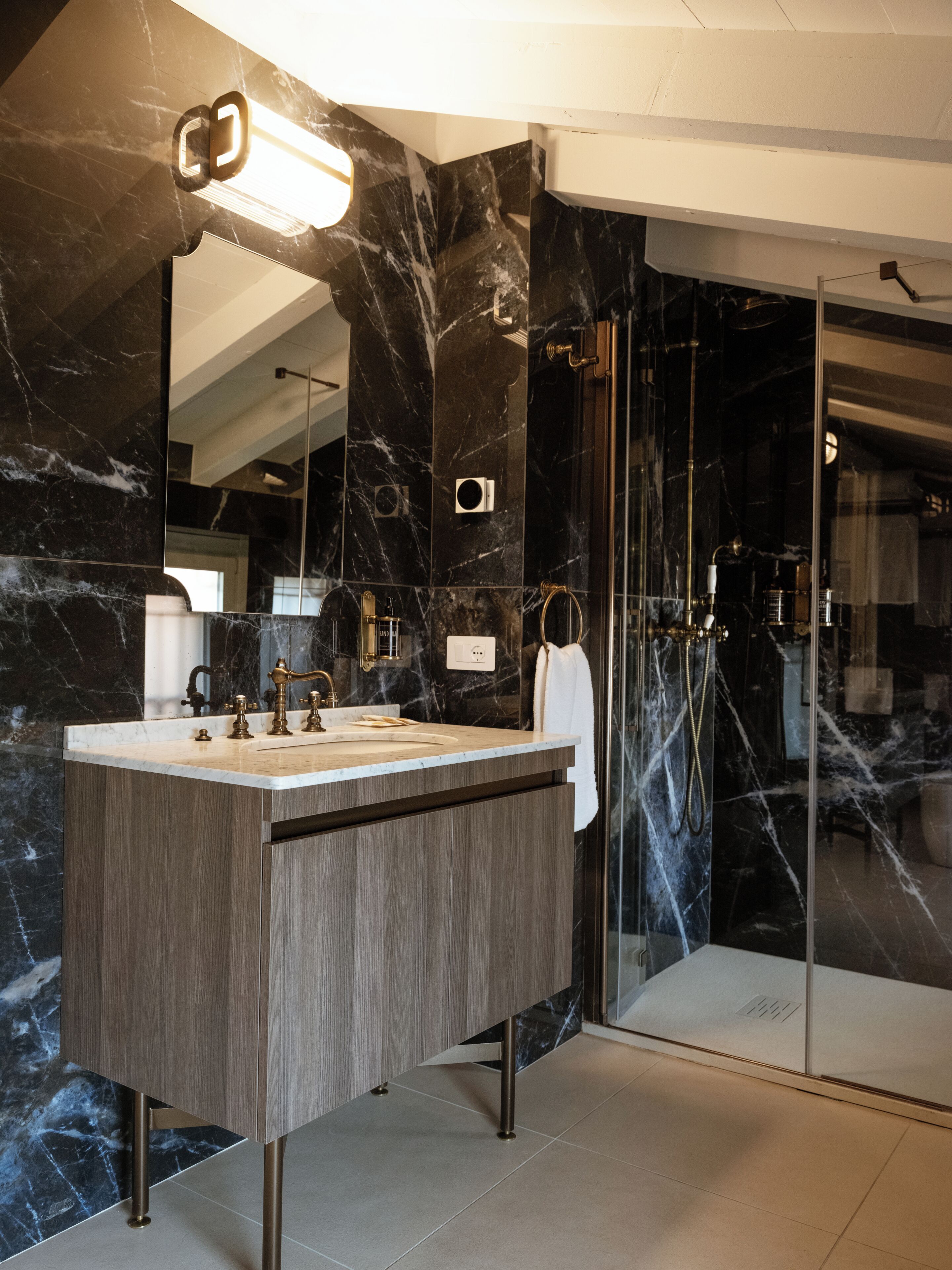 Un baño moderno con tocador de mármol, cabina de ducha de vidrio y un espejo grande.