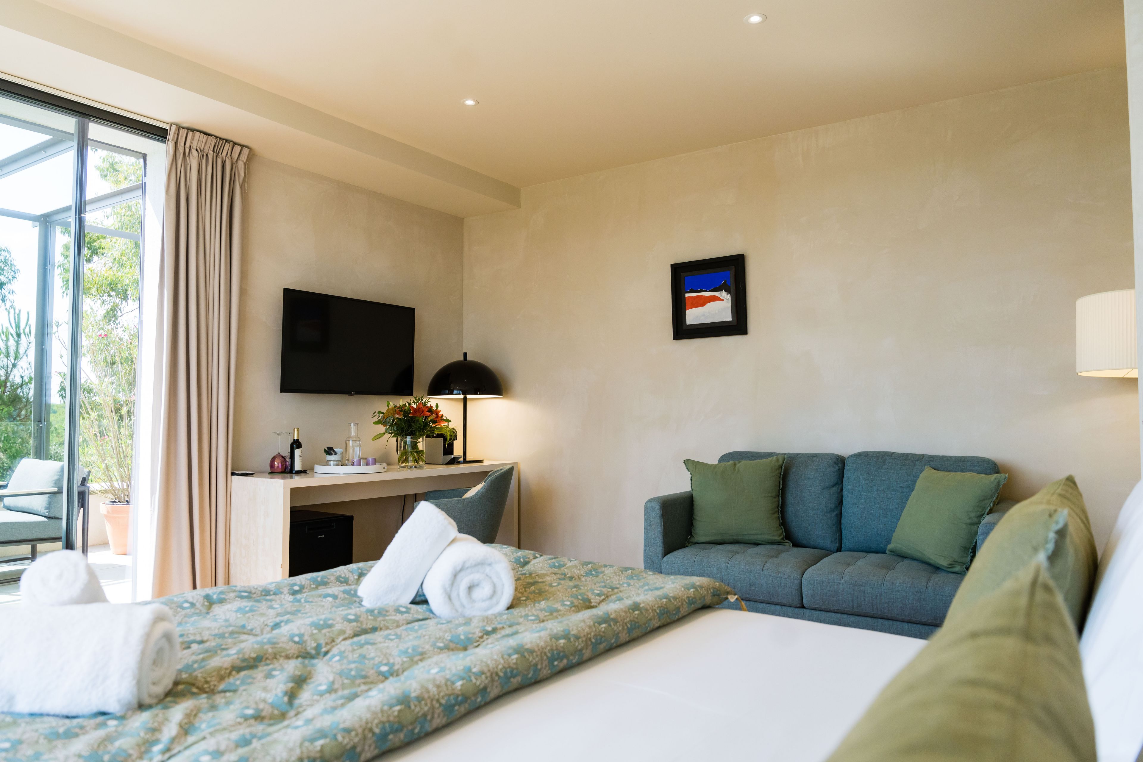Une chambre d’hôtel avec un lit, un bureau, une télévision et un canapé.