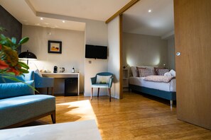 Una habitación de hotel moderna con kitchenette, sofá, cama y televisión.