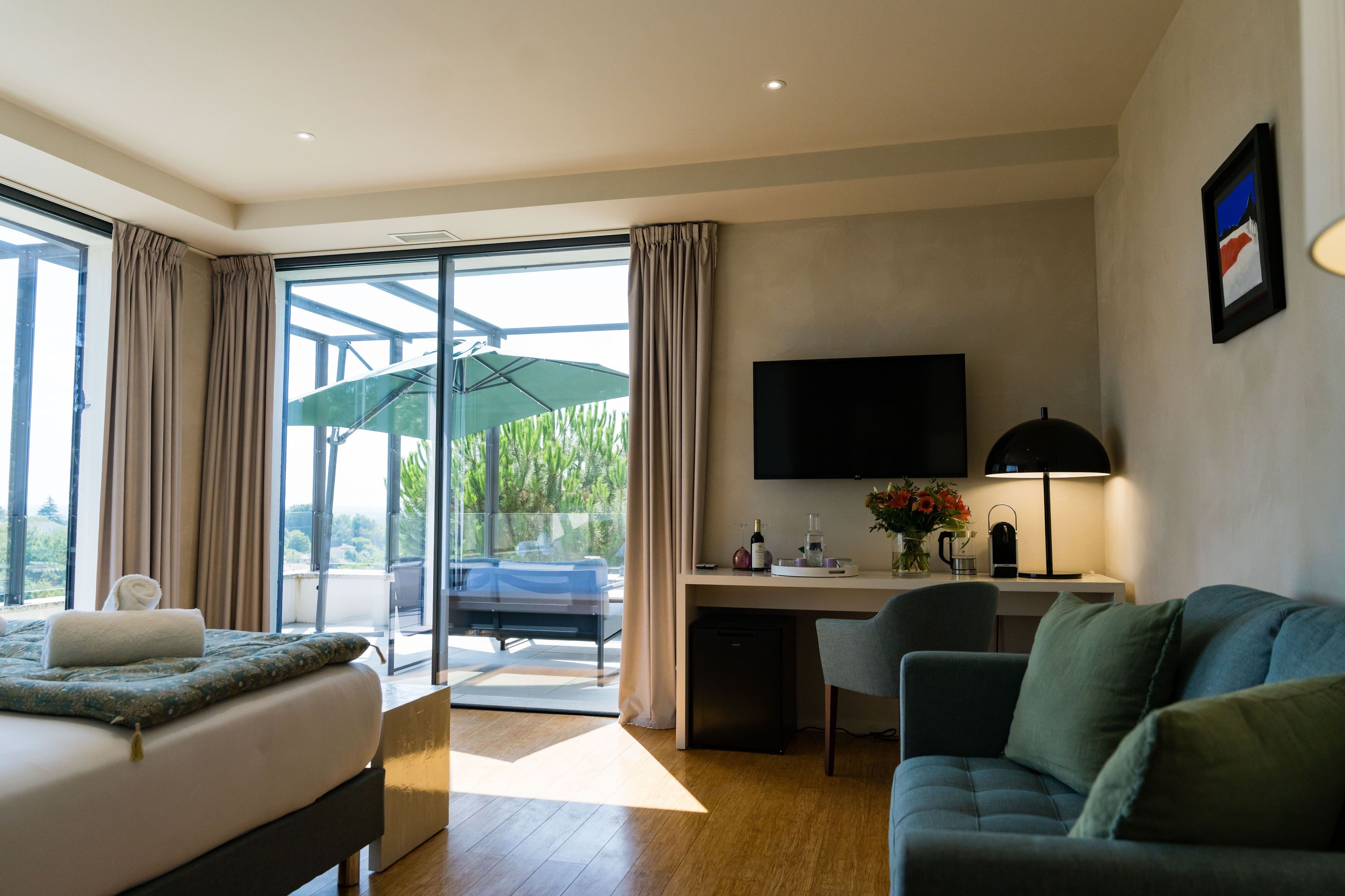 A modern hotel room with a bed, a desk, a chair, a television, and a large window with curtains.