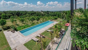 A rectangular swimming pool with a clear blue water surface, surrounded by a concrete deck and a grassy area.