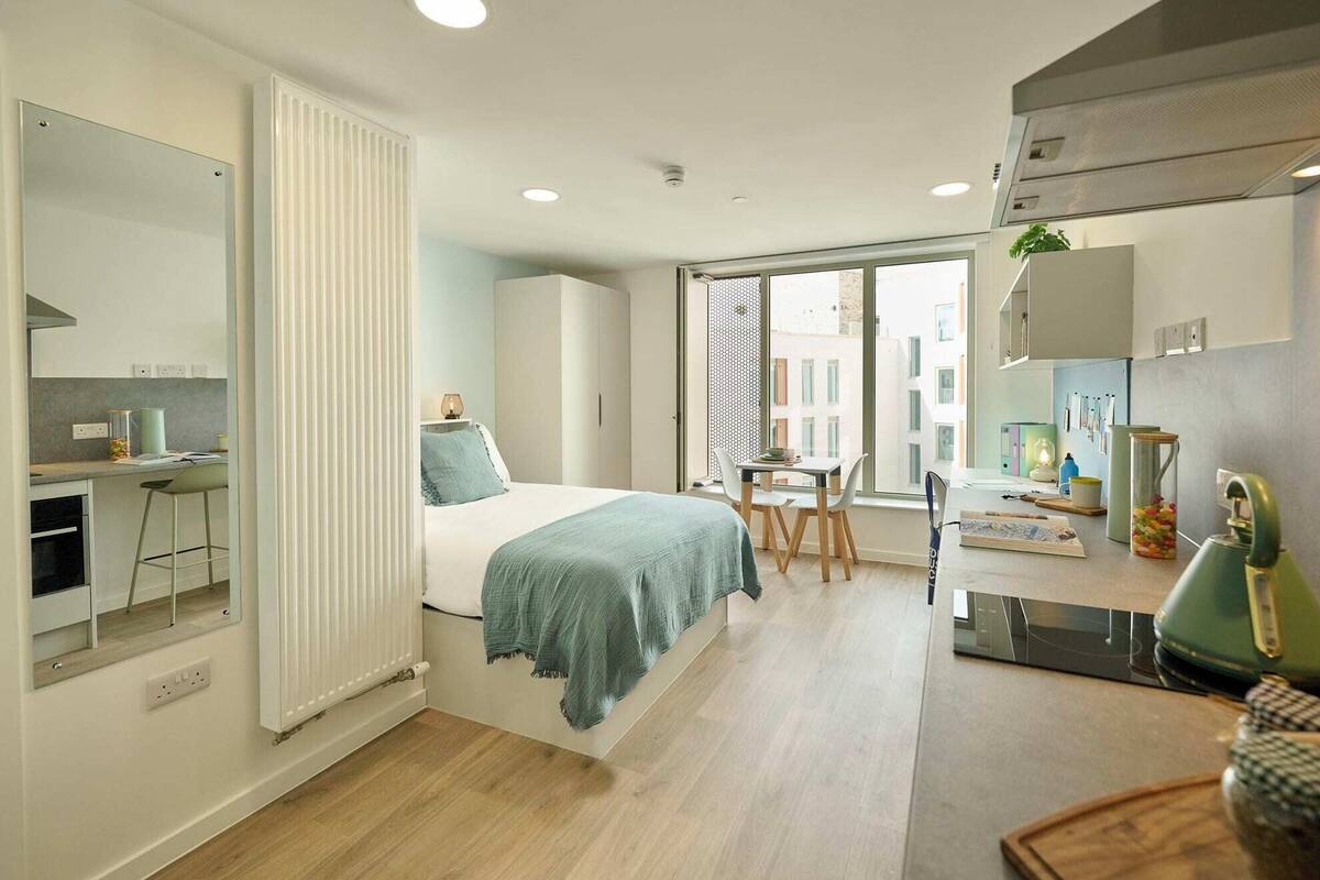 Un appartement moderne doté d’une cuisine, d’un coin repas et d’un grand lit.