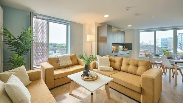 A modern living room with a sofa set, a coffee table, and a view of the city through large windows.