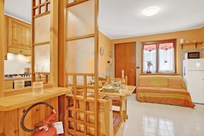 Eine kleine Küche mit Holzausstattung, einem Esstisch mit Stühlen, einem Sofa und einem Kühlschrank.