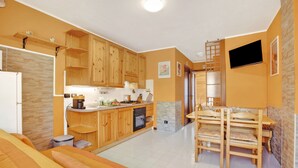 Una cocina compacta con armarios de madera, horno empotrado y un comedor con mesa y sillas.