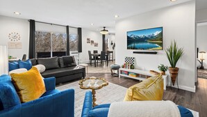 A modern living room with a sofa, coffee table, and a dining area with chairs. - Old Town Condo Near CSU Pool, Sauna, Gym & Bikes (Fort Collins)
