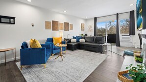 Een moderne woonkamer met een blauwe bank, een zwart hoekbank en een salontafel.