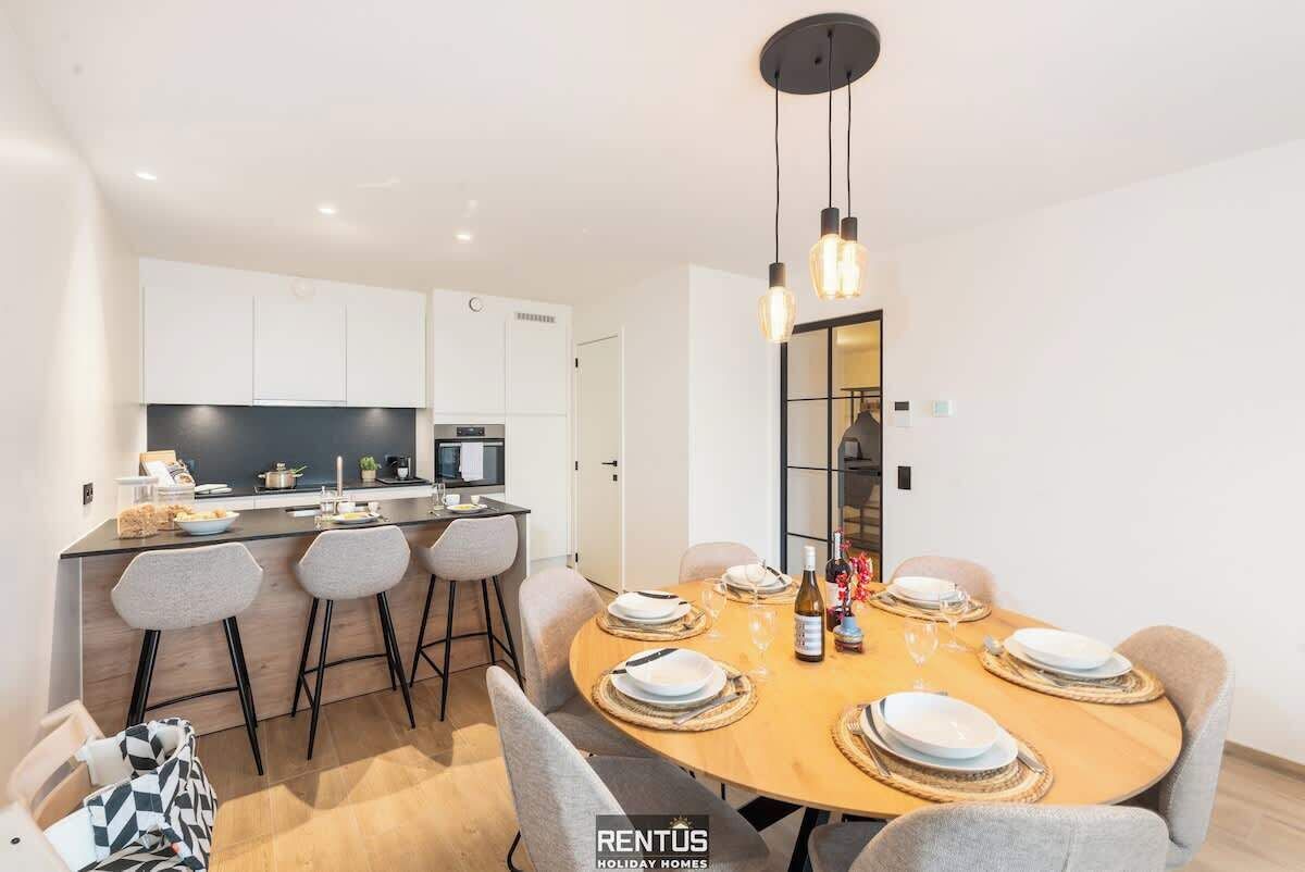 A modern kitchen with white cabinets, a central island, and a dining area with a round table set for six.